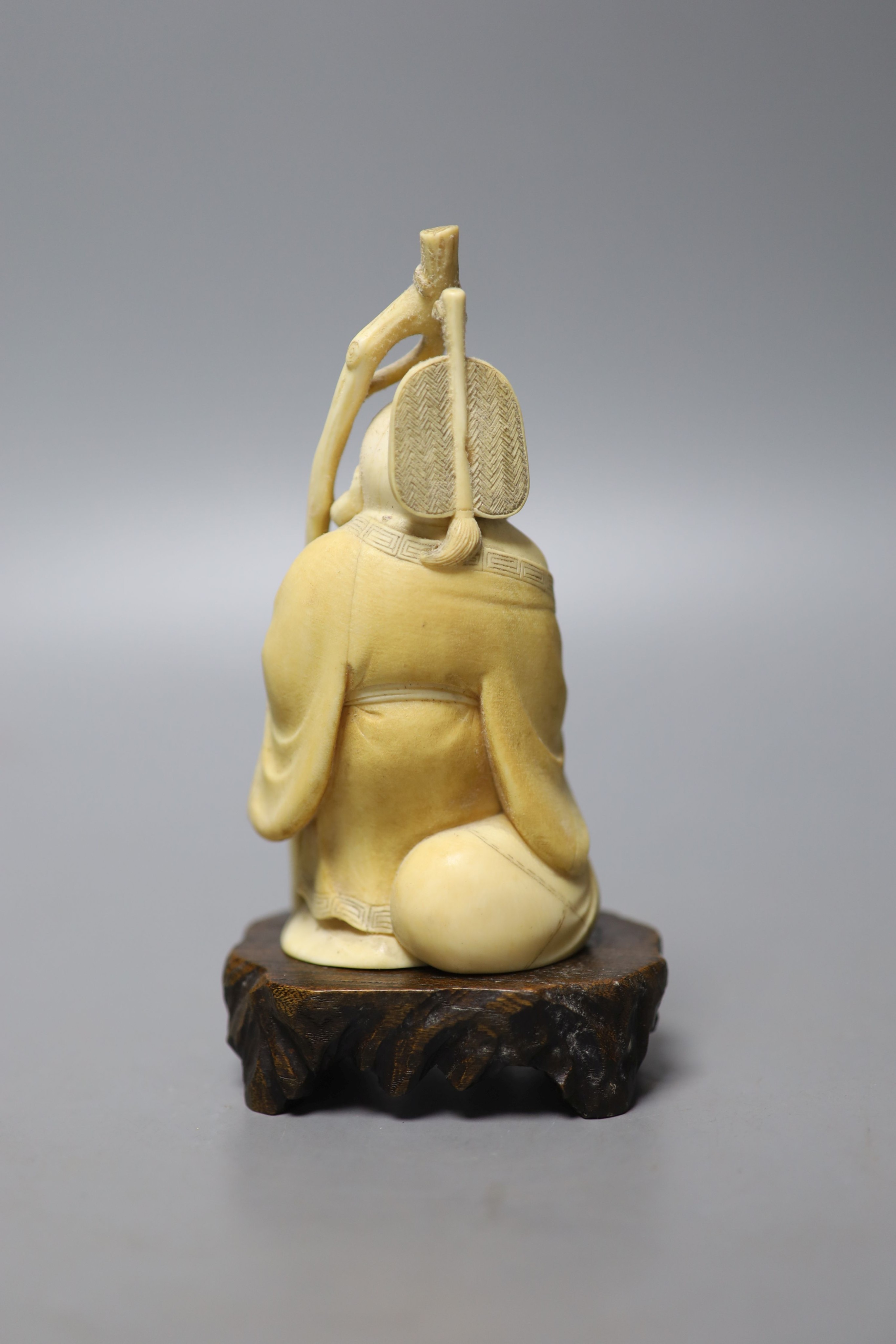 An early 20th century Japanese carved ivory okimono of Hotei, and wood stand, 15cm